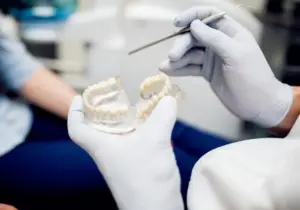 A photo of a dentist holding a dental implant.